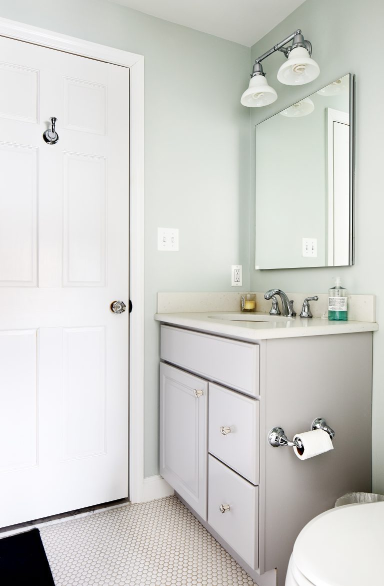 bathroom with soft color palette light green walls white floor vanity with gray cabinetry