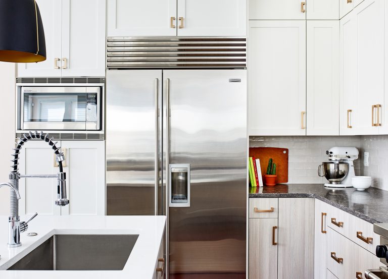 stainless steel refrigerator white cabinetry with gold hardware