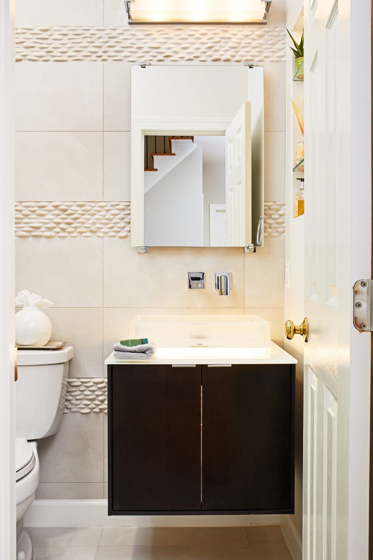 bathroom with dark wood floating vanity and textured tile stripe detail on walls