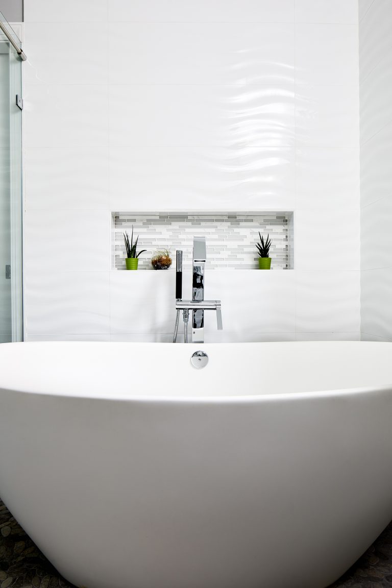 freestanding bathtub with polished chrome fixtures and built in wall nook wavy wall tile