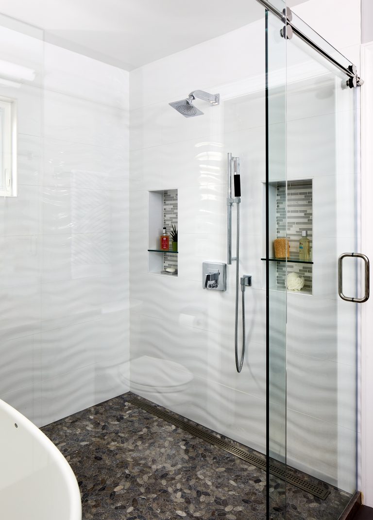 large shower stall with glass doors storage nooks built into wall wavy wall tile