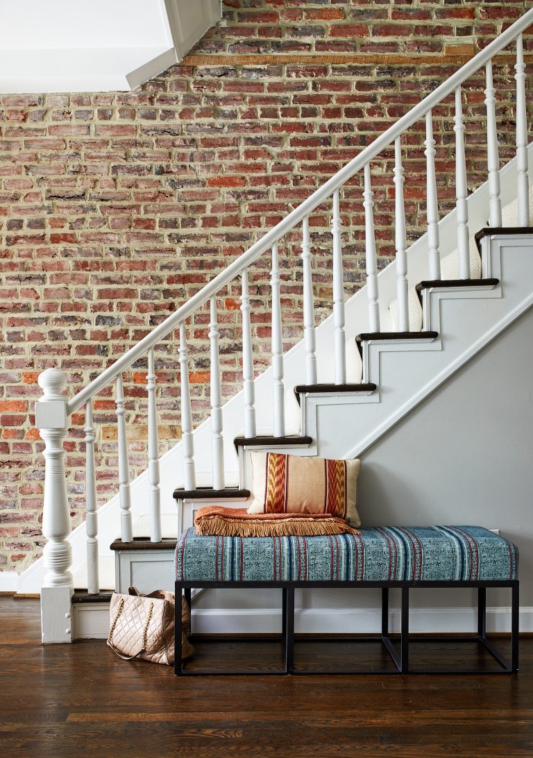 exposed brick wall in entryway along staircase dark wood floors