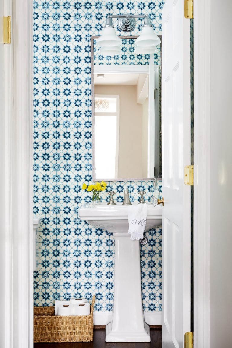 first floor powder room with pedestal sink, wood floors, and teal geometric wall tile