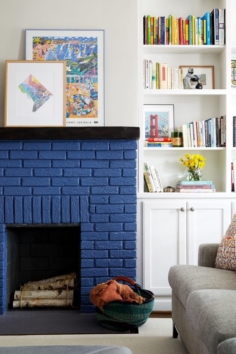 blue painted brick fireplace with dark wood mantle and built in bookcases in living room