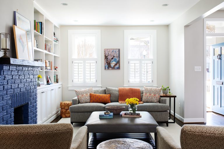 bright living area with built in bookcases and brick fireplace painted blue