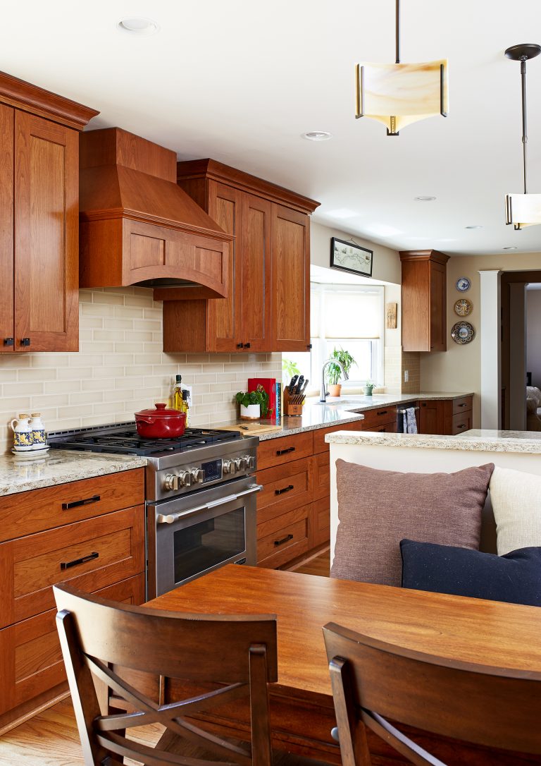 view from kitchen eat in area medium stained cabinetry and vent hood stainless steel gas range