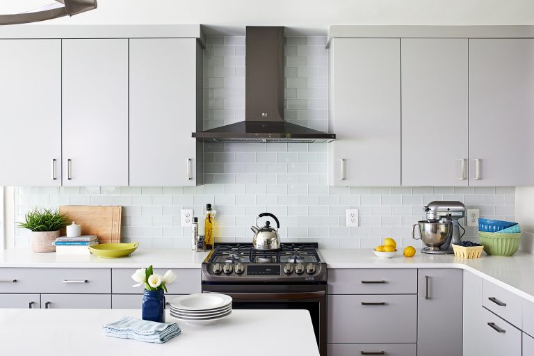white and gray cabinetry dark stainless steel appliances glass subway tile backsplash