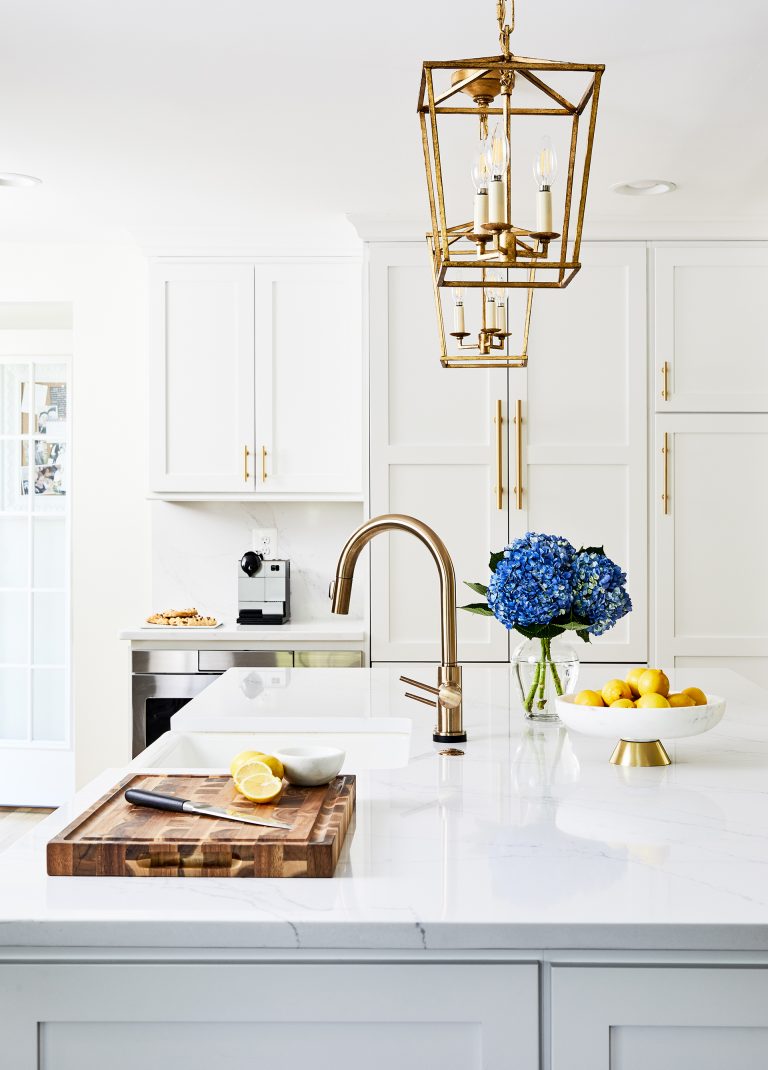 white cabinetry and countertops gold fixtures hardware and pendant lighting