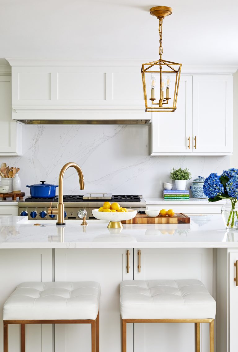 kitchen with white cabinetry gold hardware and accents marble backsplash