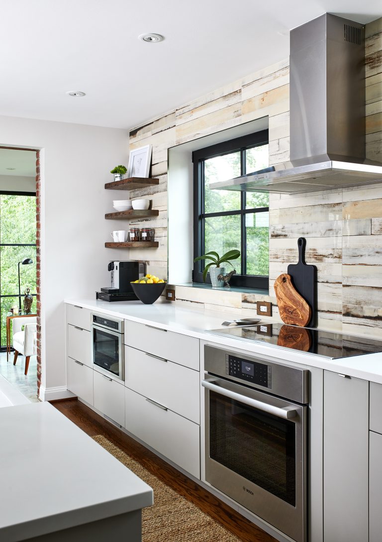 sleek white shiny cabinetry stainless steel appliances open shelving and natural color statement tile backsplash