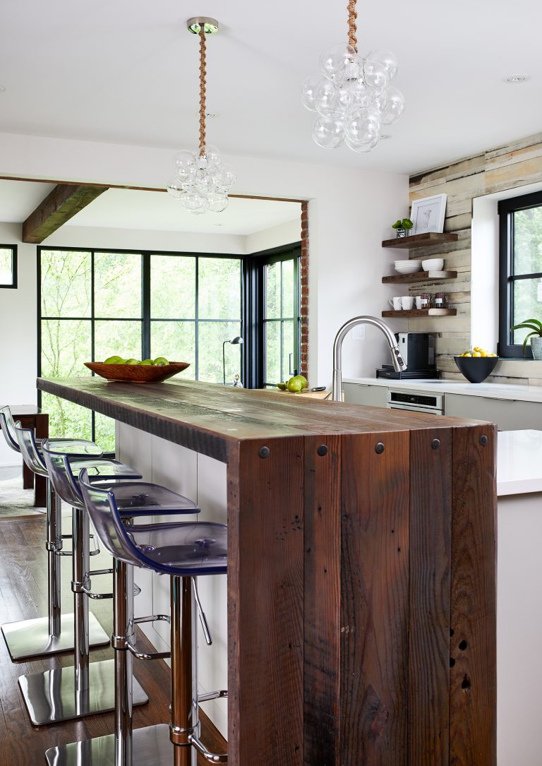 kitchen island with wood waterfall edge countertop and bar height seating pendant lighting