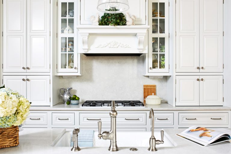 kitchen remodeling with large white tall cabinets with silver knobs and white hood range above stove plate