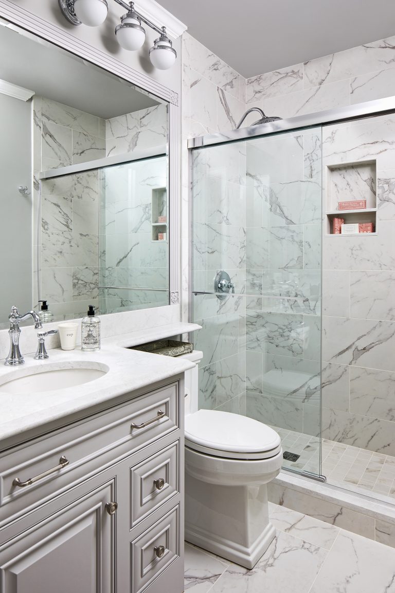 white and grey bathroom with marble shower walls and semi-frameless shower doors