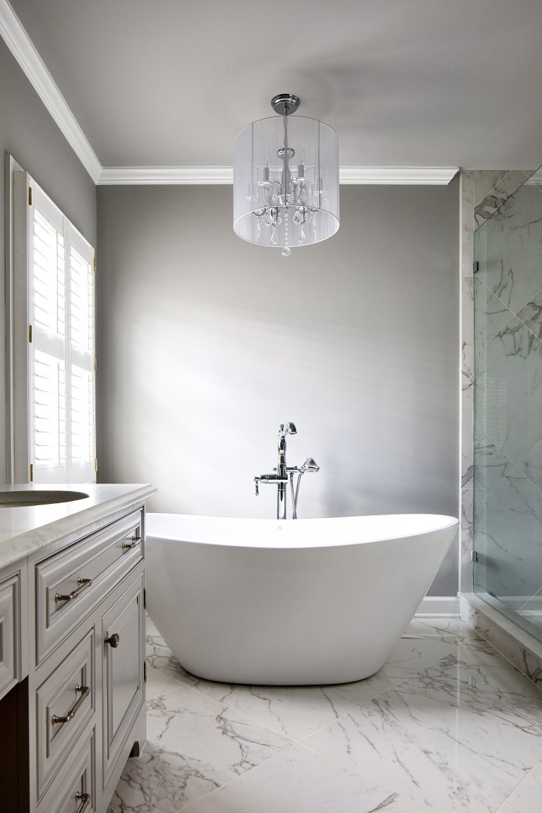 white freestanding one-piece soaking bathtub with center drain and glass light pendant over oval bathtub