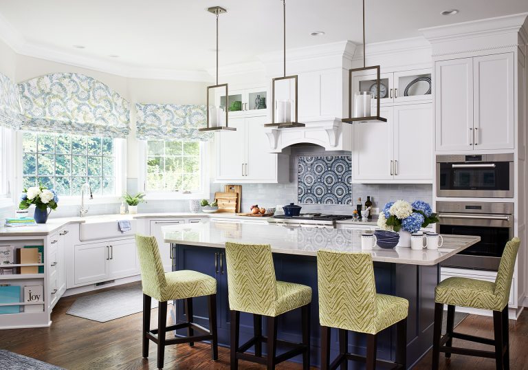 transitional white painted wooden kitchen cabinets with marble granite countertop and white and blue backsplash also triple pendant lamps over kitchen island with seating