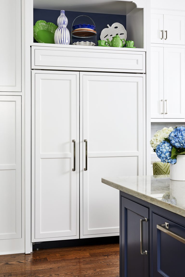 white kitchen wood panel hidden French door refrigerator with pull handles surrounding white cabinets