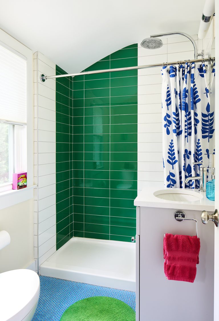 green and white tile bathroom with one sink vanity and mirror