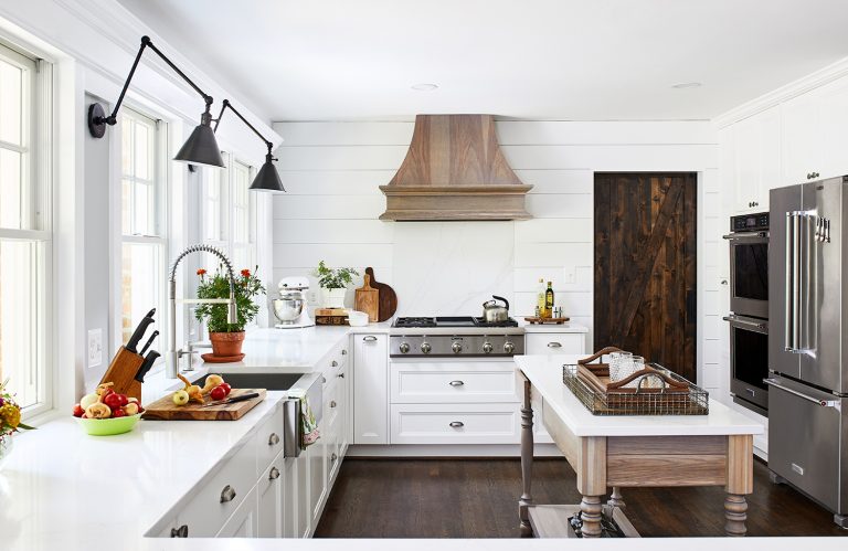 maryland kitchen with two lamps wall light fixtures, farmhouse apron sink, white cabinets and drawers with pull handles. Stainless steel appliances and dark wooden door