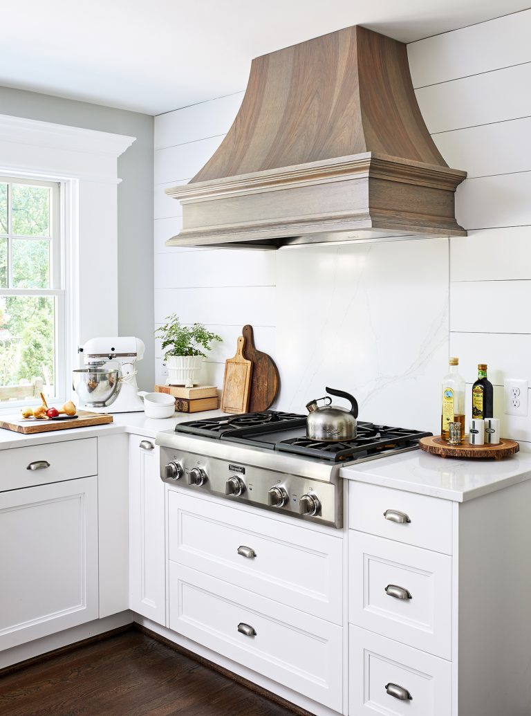 wooden hood range above stainless stain 5 sealed burners cooktop with white cabinets with pull handles