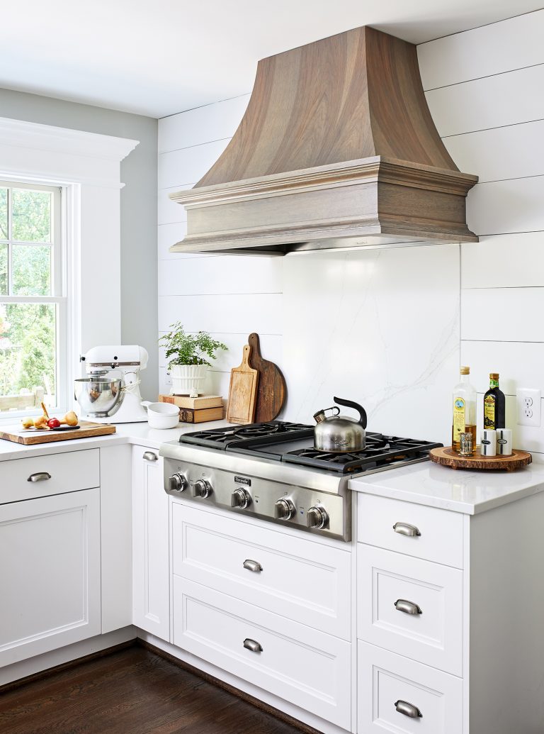 wooden hood range above stainless stain 5 sealed burners cooktop with white cabinets with pull handles