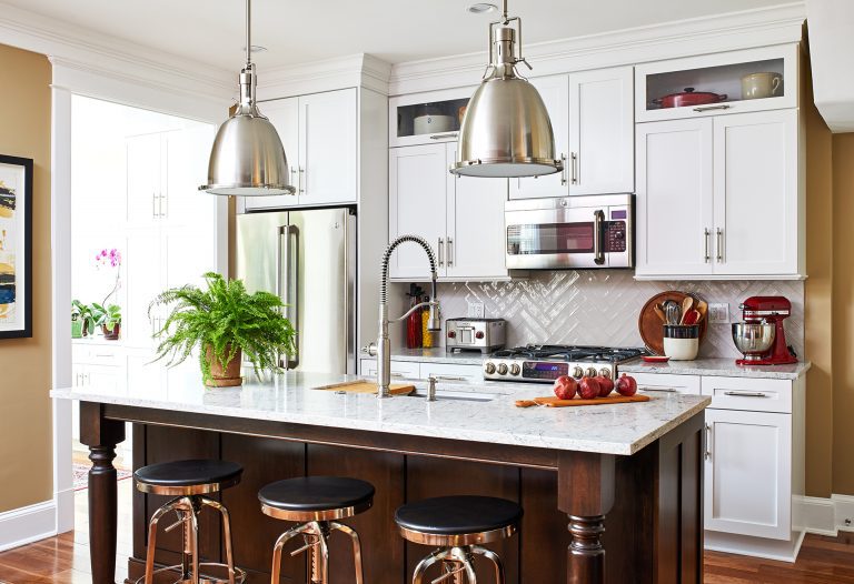 transitional kitchen with dark island, marble counters, pendant lighting