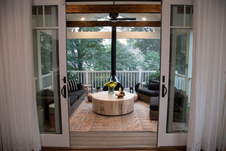 white sliding doors with white curtains, black patio furniture and wooden round table