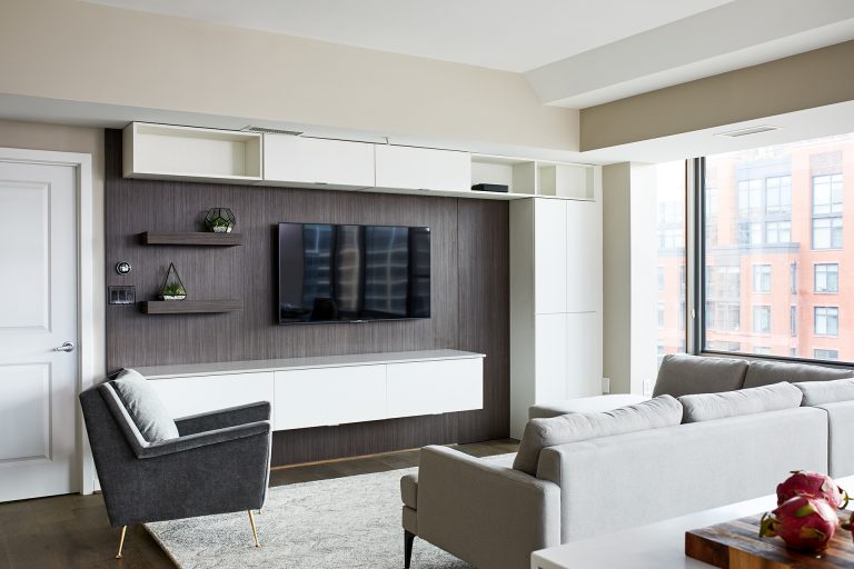 angled living room with floating shelves and hanging cabinet with tv wall mount on half a dark brown wall