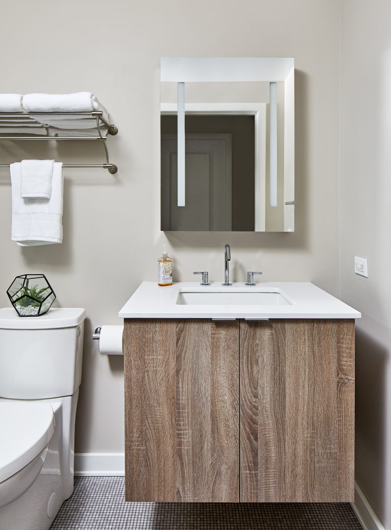case design bathroom with single sink with cabinets doors above rectangular mirror
