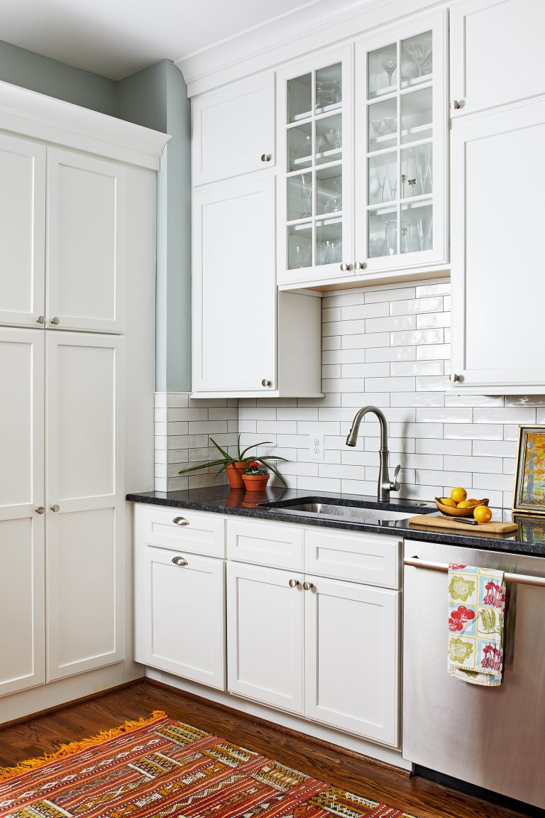 stainless undermount sink with black granite countertop, white tall kitchen cabinets, floating cabinets with glass doors