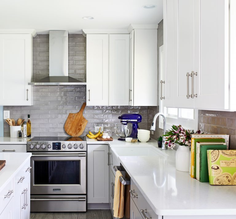 white kitchen counter with grey brink backsplash, stainless steel appliances and hood range