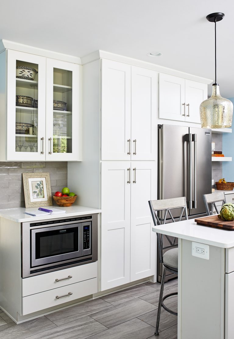 microwave under kitchen countertop and white cabinets with pull handles around the refrigerator