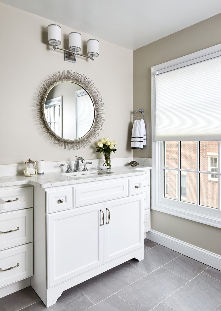cabinet finish white bathroom with single sink and round wall mirror with traditional white framed windows