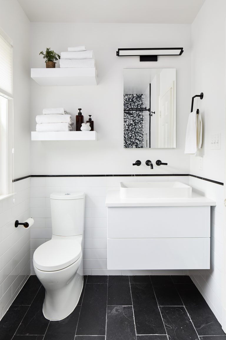 black faucets with light fixture add small but strong accents to this mostly white bath