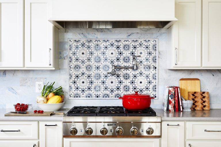 white paneled kitchen hood with blue and white back splash