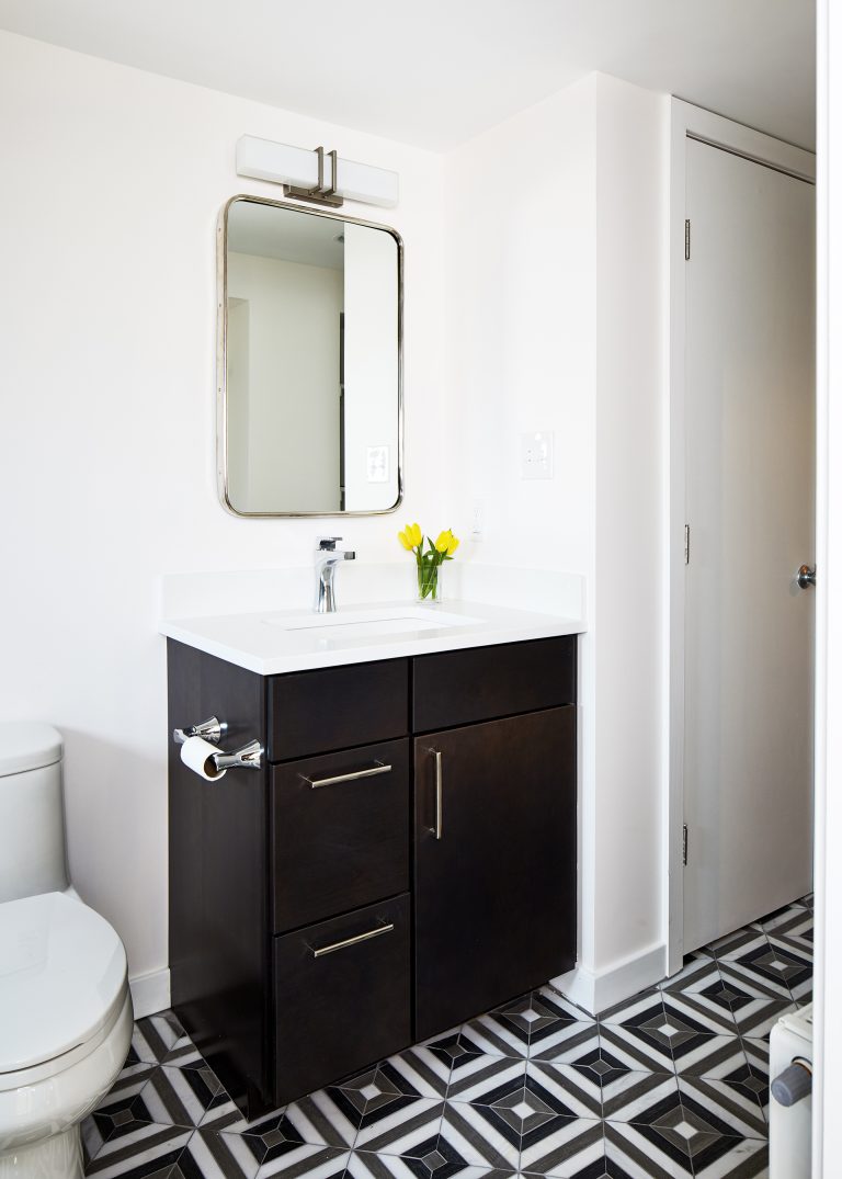 Black and white floor tiles with single sink vanity with mirror