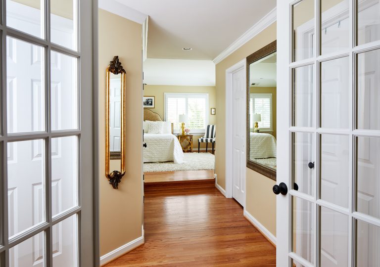 maryland home remodeling with double glass doors leading to master bedroom with light wood flooring and white area rug that matches the window trim and bed covers