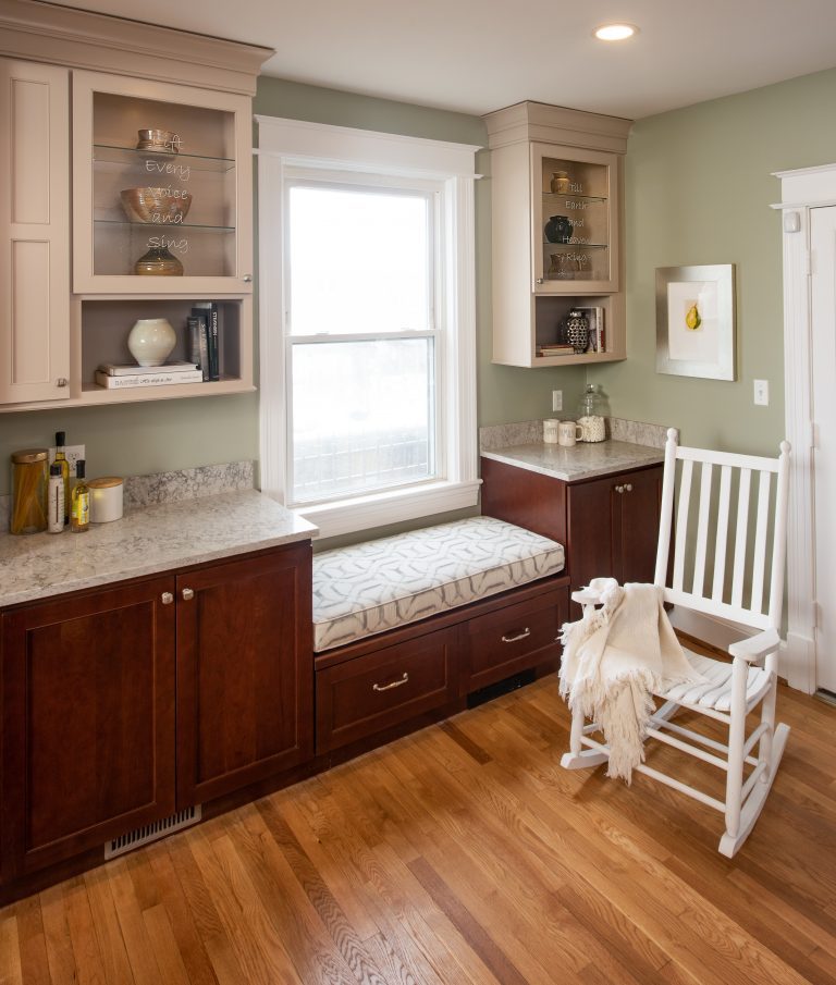 Bay window seat in kitchen with wood flooring and white see thru glass cabinets