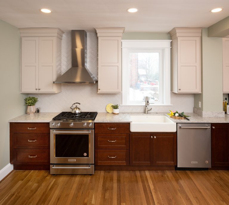 Kitchen remodeling dc Stainless steel hood range in between two white cabinets above stove top