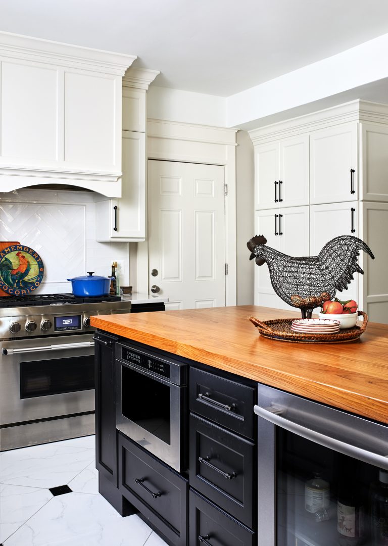 black appliance with wood kitchen island and white cabinets with black handles