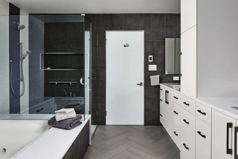 Large master bathroom with white cabinets and black handlers
