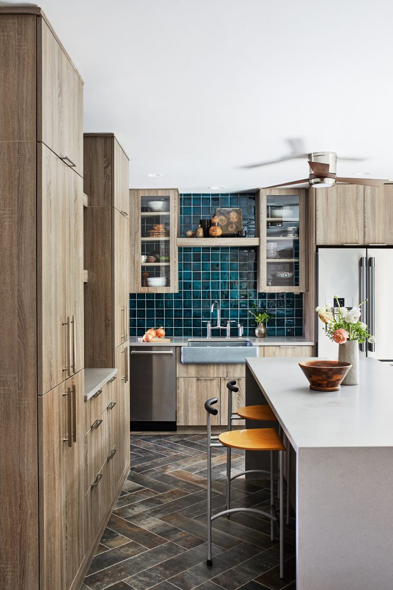 kitchen with natural wood cabinetry teal tile and island with waterfall edge countertop and seating