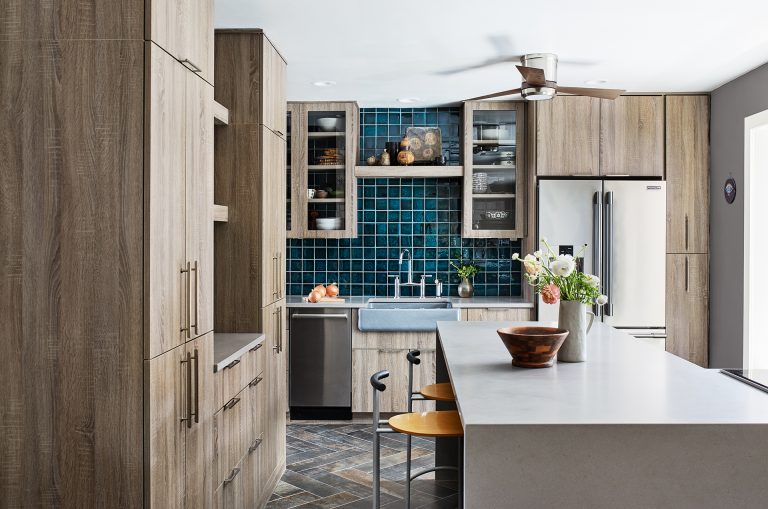 kitchen with natural wood cabinetry teal tile and island with waterfall edge countertop and seating