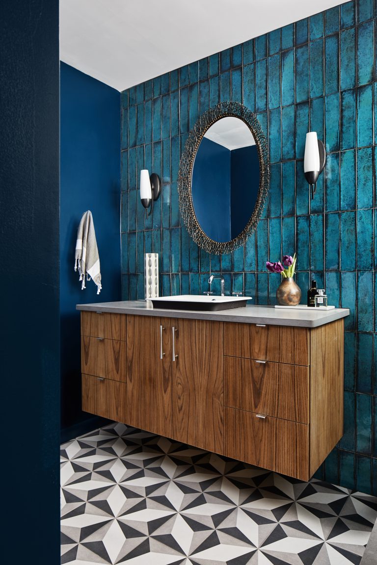 bathroom with geometric tile floors and teal tile feature wall behind floating vanity