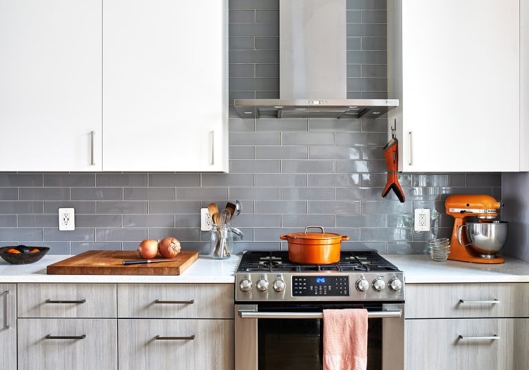 kitchen with gray subway tile backsplash stainless steel range and hood