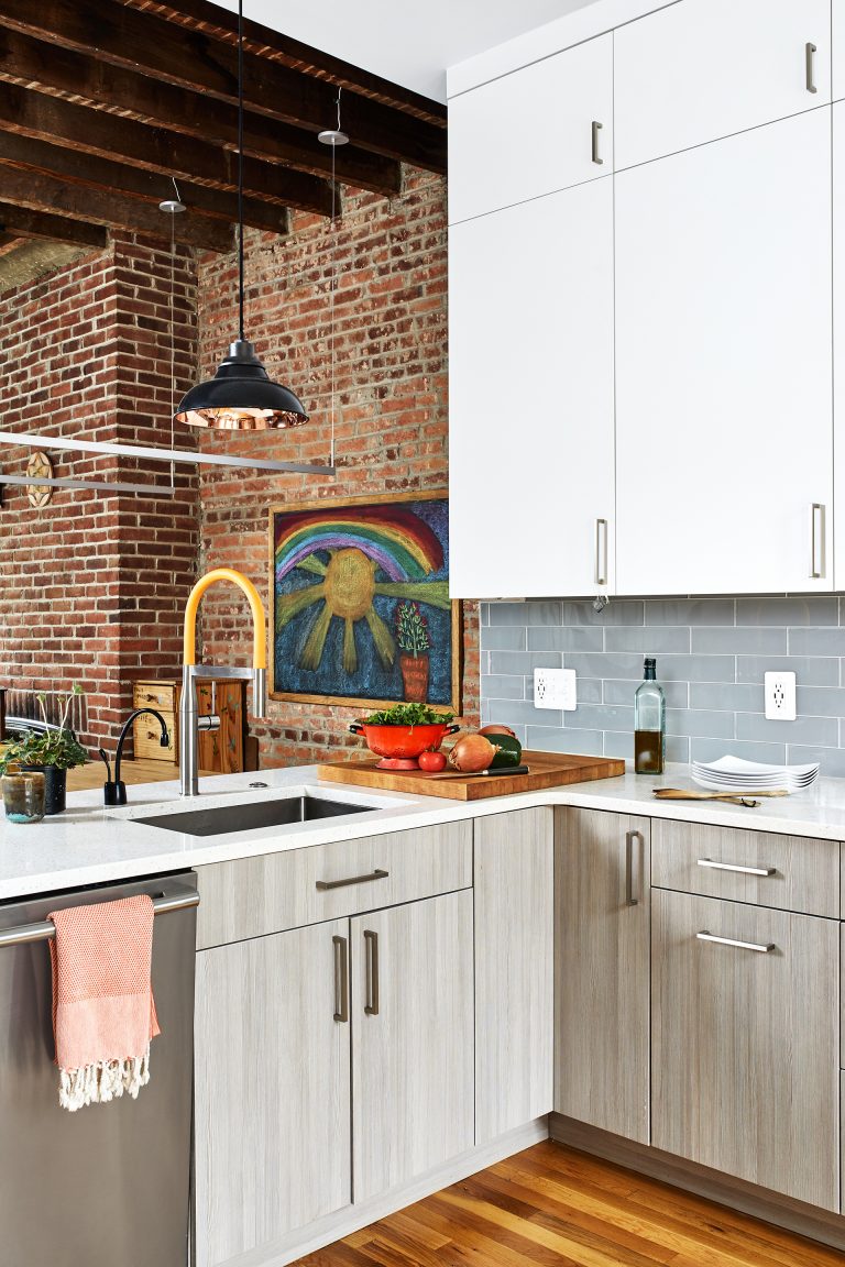 kitchen with gray lower cabinets and white upper cabinets stainless steel appliances peninsula with sink open to dining area with exposed brick and wood beams