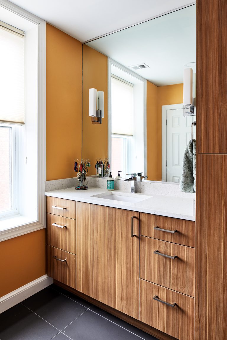 renovated bathroom with natural wood cabinetry orange walls black tile floors plenty of storage