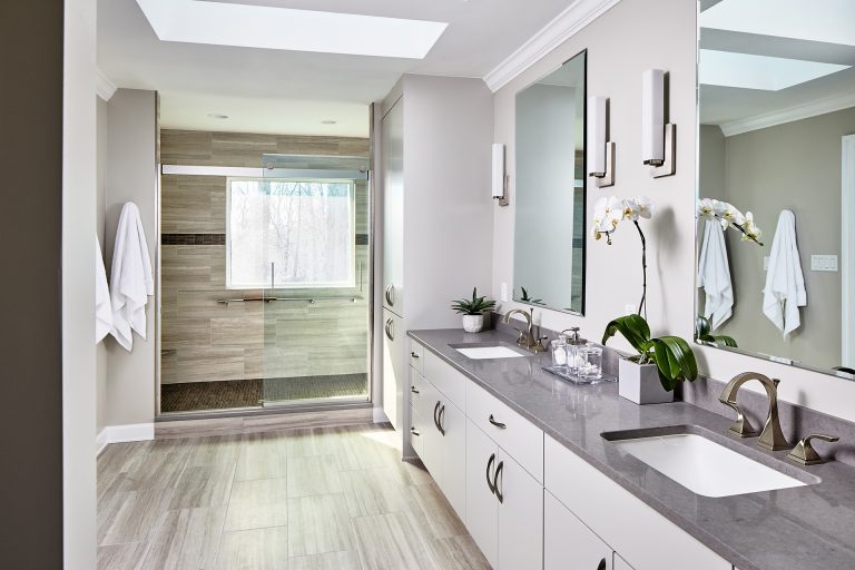 Large bathroom with white cabinets, double sink vanity, large shower with sliding doors and two frameless windows