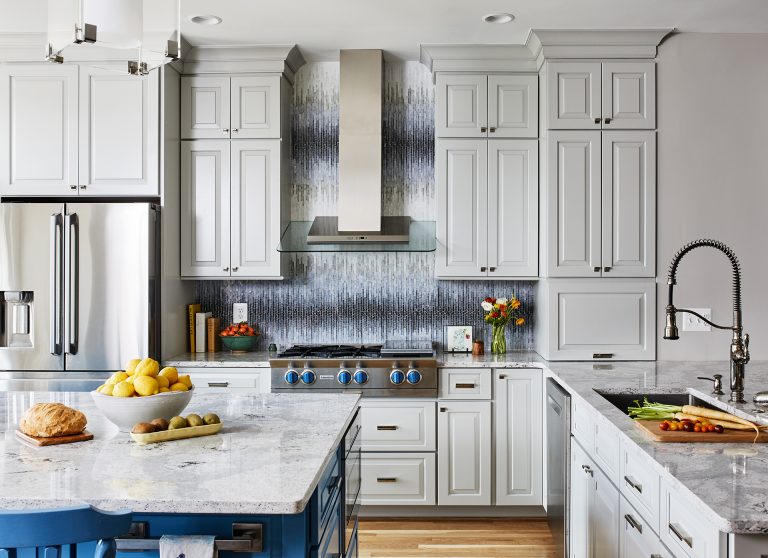 kitchen with white cabinetry wood floors blue island mosaic backsplash stainless steel appliances