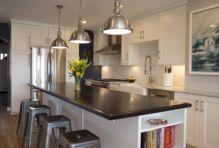 seating at kitchen island with black countertops and open side storage pendant lighting
