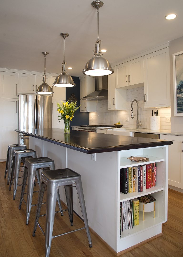 seating at kitchen island with black countertops and open side storage pendant lighting